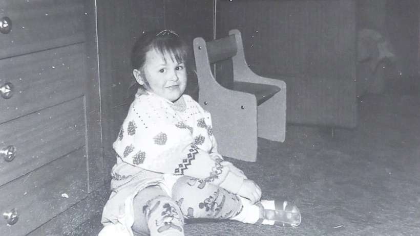 Me as a child sitting on the floor, puting a sandal on while looking straight to the camera. What a poser!