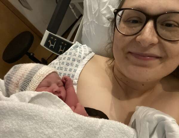 A woman in a hospital bed holding her newborn baby shortly after birth, featured in a personal birth story.