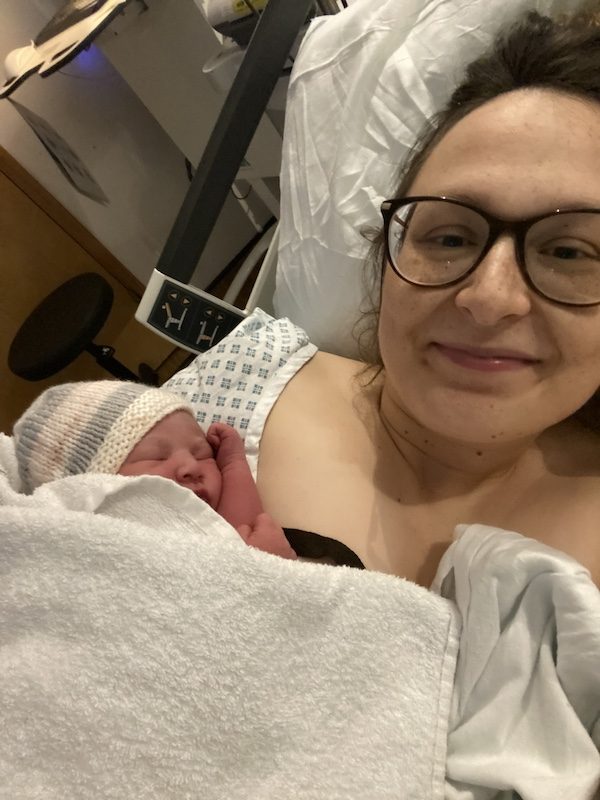 A woman in a hospital bed holding her newborn baby shortly after birth, featured in a personal birth story.